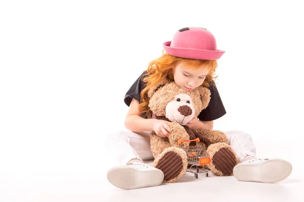 Kid playing with teddy bear and shopping car toy on white — Stock Photo
