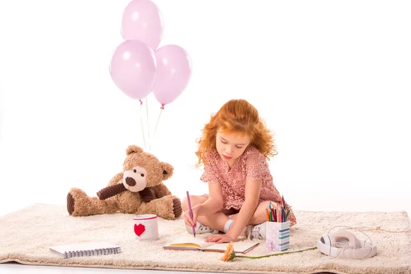 Niño sentado en la alfombra y dibujo en cuaderno aislado en blanco - foto de stock