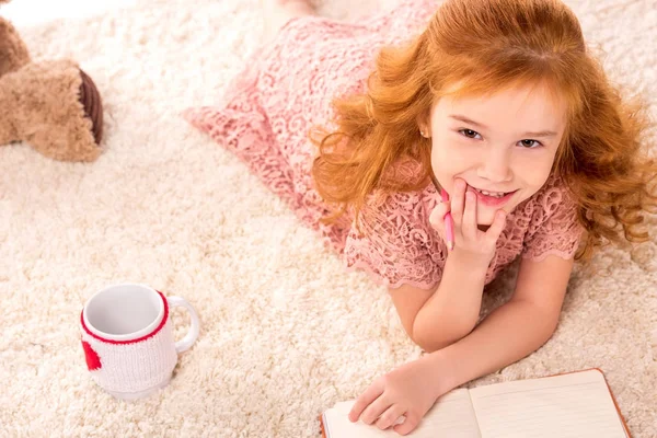 Overhead view of dreamy redhead kid lying on fluffy carpet — Stock Photo