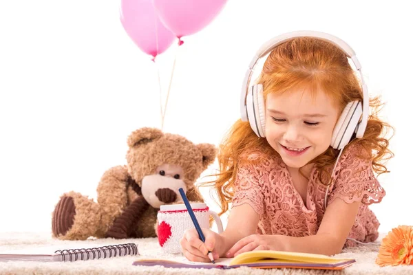 Niño sonriente dibujando y escuchando música aislada en blanco - foto de stock
