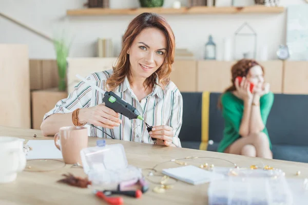 Attraente giovane donna con pistola colla rendendo accessori di perline — Foto stock