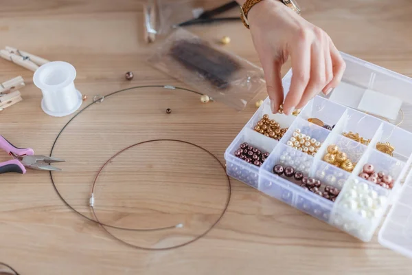 Cropped shot of woman making necklace of beads — Stock Photo