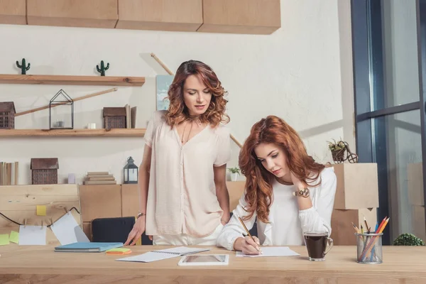 Señora jefe mirando a la gerencia mientras ella toma notas - foto de stock