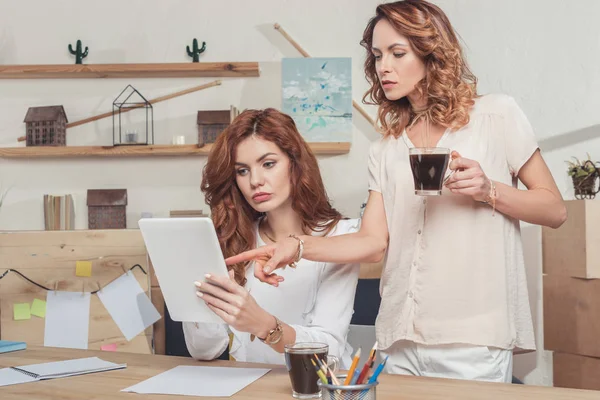 Jovens empresárias que trabalham juntas enquanto bebem café — Fotografia de Stock