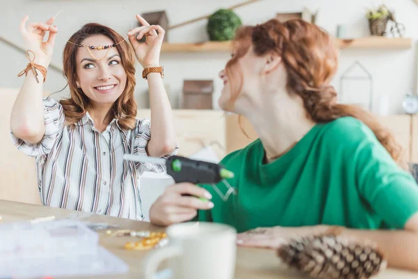 Young women trying on handmade necklace at workshop — Stock Photo