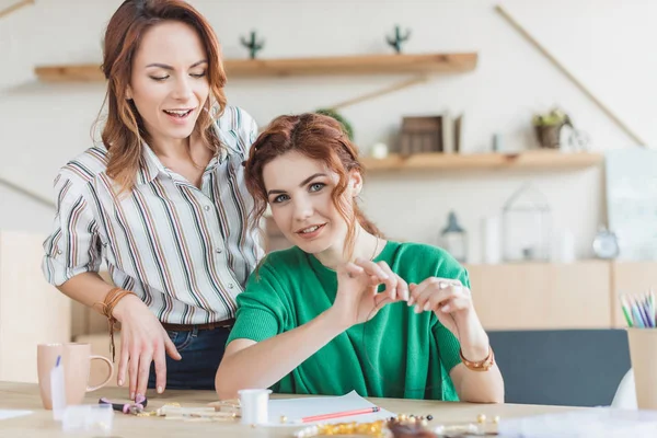 Belles jeunes femmes faisant des accessoires de perles en atelier — Photo de stock