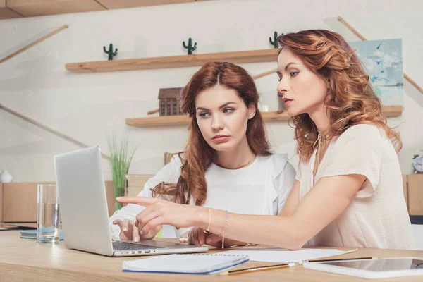 Hermosas mujeres de negocios jóvenes que trabajan con el ordenador portátil juntos en la oficina - foto de stock