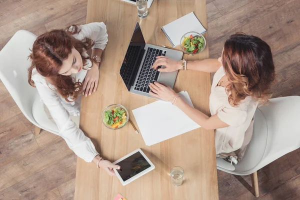 Vista superior de buisnesswomen almoçando juntos e usando dispositivos no escritório — Fotografia de Stock