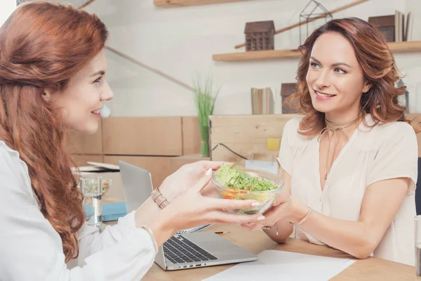 Красивые молодые коллеги делятся здоровым салатом в офисе — стоковое фото
