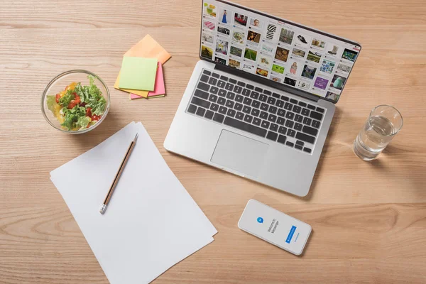 Top view of workplace with digital devices and bowl of salad — Stock Photo