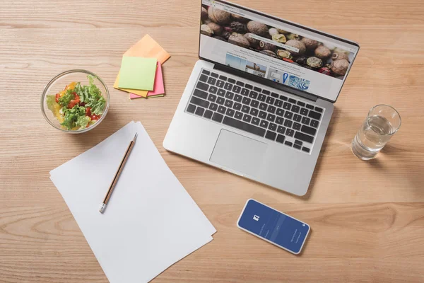 Vue du dessus du lieu de travail avec ordinateur portable, smartphone et salade saine — Photo de stock