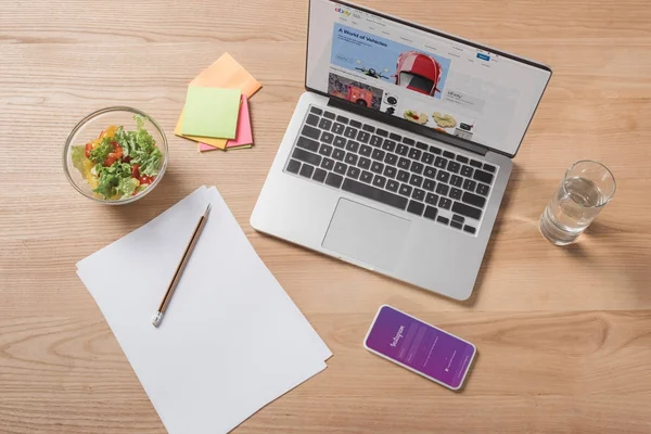 Vue du dessus du lieu de travail avec ordinateur portable, smartphone et salade fraîche — Photo de stock