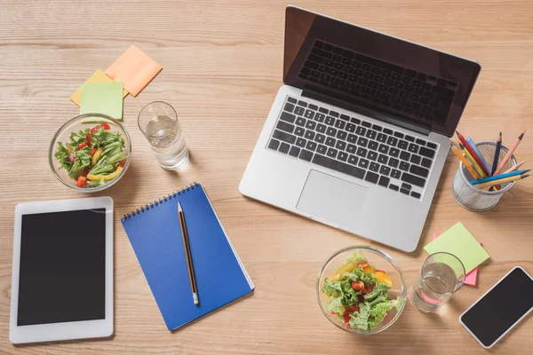 Arbeitsplatz von oben mit digitalen Geräten und gesundem Salat — Stockfoto