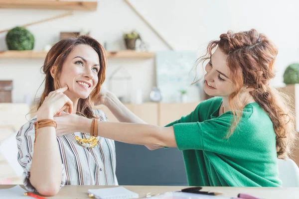 Mujeres jóvenes probándose accesorios hechos a mano en el taller - foto de stock