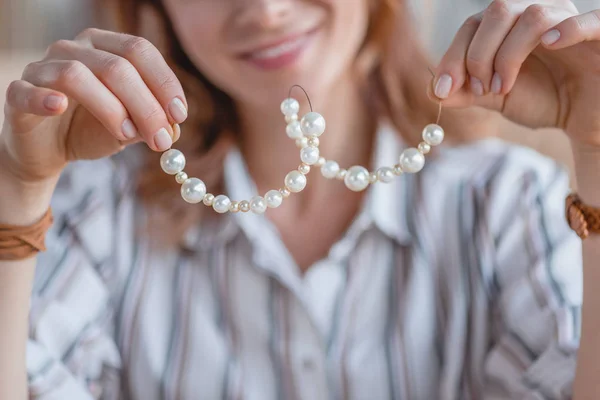 Tiro recortado de mujer joven sosteniendo chaplet hecho a mano de cuentas - foto de stock