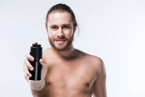 Cheerful young man holding deodorant spray in outstretched hand — Stock Photo