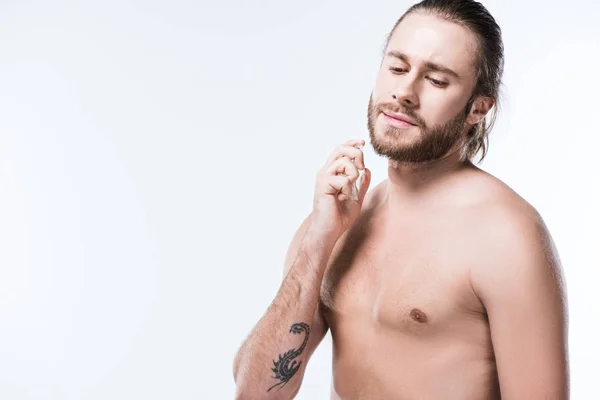 Joven sosteniendo botella de vidrio con perfumes contra su cuello, aislado en blanco - foto de stock