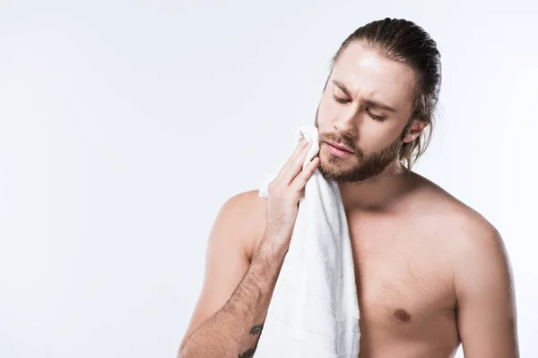 Bearded caucasian man with wet hair holding bath towel in hands while his eyes closed, isolated on white — Stock Photo