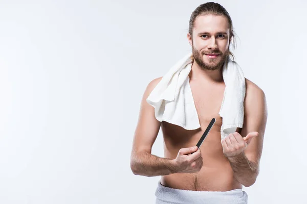 Beau jeune homme avec serviette de bain autour de son cou tenant lime à ongles, isolé sur blanc — Photo de stock
