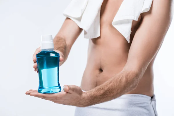 Midsection of man with bath towel on shoulder and around waist holding bottle of tooth rinse in hands, isolated on white — Stock Photo