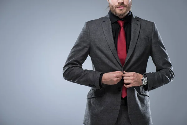 Imagen recortada de hombre de negocios abotonando su chaqueta, aislado en gris - foto de stock