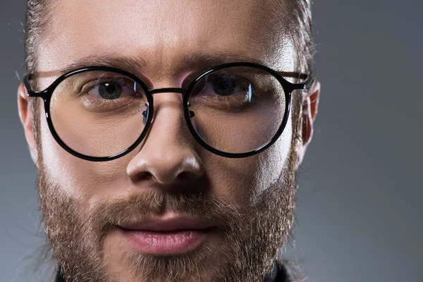 Porträt eines gutaussehenden bärtigen Mannes mit Brille, isoliert auf grau — Stockfoto