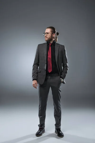 Geschäftsmann mit Brille, der mit der Hand in der Jackentasche wegschaut, isoliert auf grau — Stockfoto