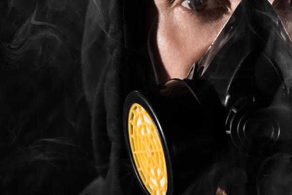 Hombre de capucha negra con máscara protectora rodeada de nubes de humo — Stock Photo