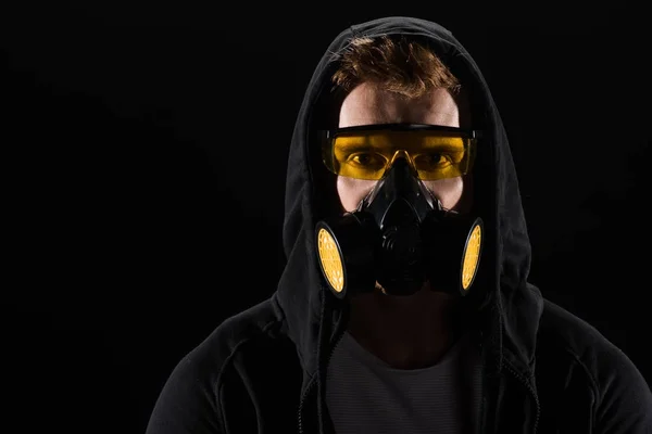 Hombre de capucha negra con gafas protectoras y máscara de filtro aislado en negro - foto de stock