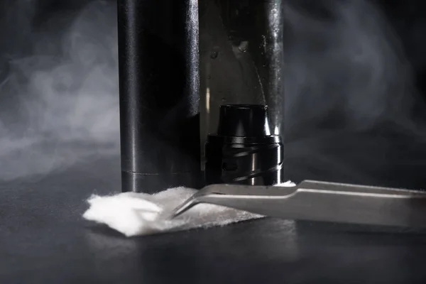 Cigarette électronique et liquide avec nuages de fumée sur fond sombre — Photo de stock