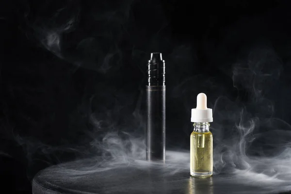 Sigaretta elettronica e liquido con nuvole di fumo su sfondo scuro — Foto stock