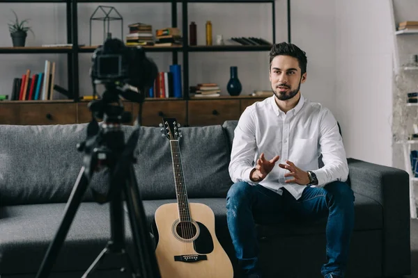 Music blogger sitting on sofa and talking about acoustic guitar — Stock Photo