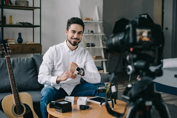 Sonriente blogger tecnológico poniéndose un nuevo reloj inteligente - foto de stock