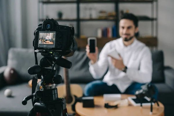 Blogueur de la technologie pointant sur un nouveau smartphone avec caméra au premier plan — Photo de stock