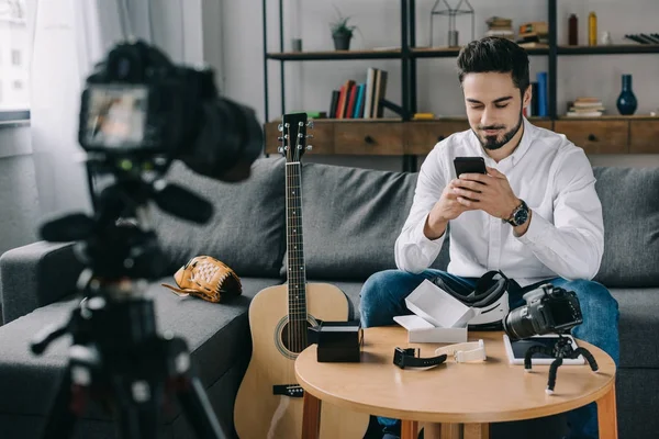 Guapo blogger de tecnología mirando el teléfono inteligente - foto de stock