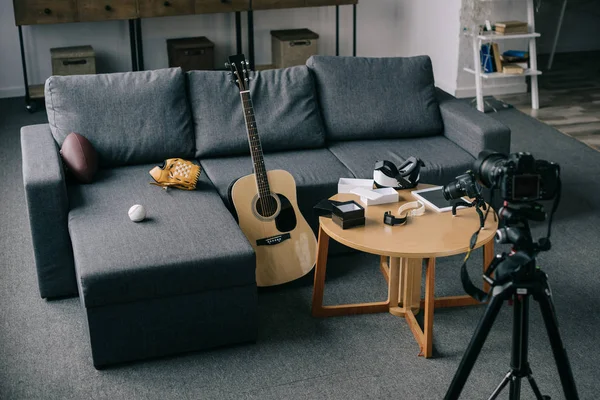Guitare acoustique et caméras avec canapé gris dans une pièce vide — Photo de stock
