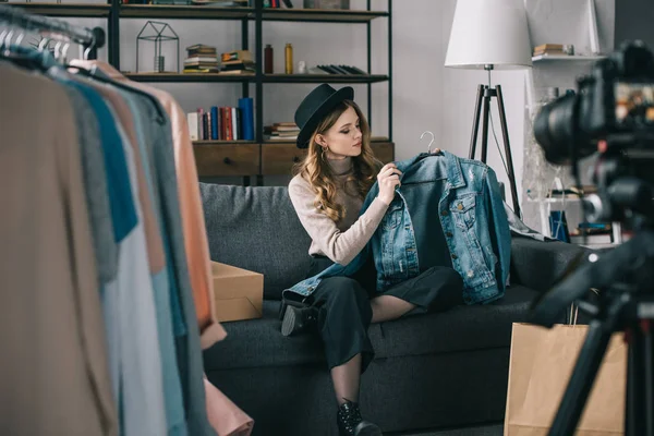 Молодой блогер моды сидит перед камерой в джинсовой куртке — стоковое фото