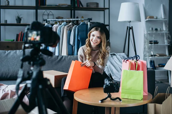 Smiling fashion blogger sitting with shopping bags and recording new video for vlog — Stock Photo