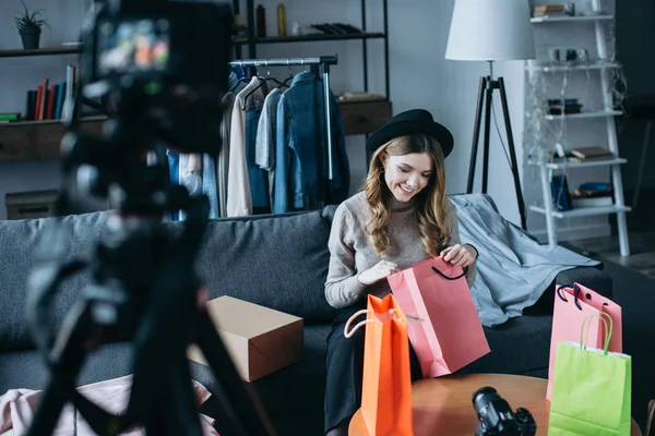 Sonriente blogger de moda mirando en bolsas de la compra y la grabación de nuevo video para vlog - foto de stock