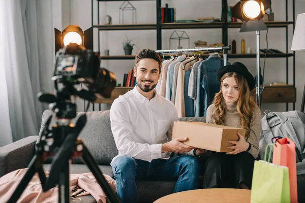 Blogueurs de mode souriants assis avec la boîte devant la caméra — Photo de stock