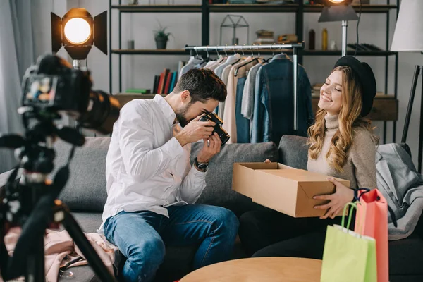 Photographer shooting fashion blogger with new clothes in box — Stock Photo