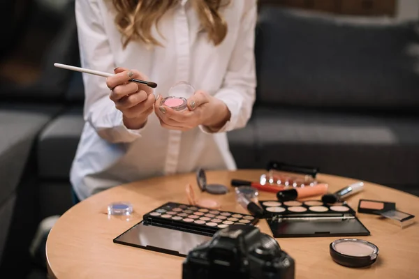 Cropped image of beauty blogger holding makeup brush and eyeshadow in hands — Stock Photo
