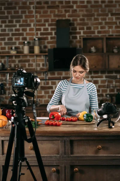 Junge schöne Food-Bloggerin schneidet Kirschtomaten — Stockfoto