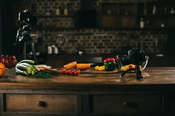 Table en bois avec légumes, fruits et appareils photo — Photo de stock