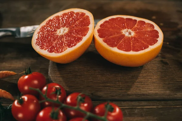 Pompelmo tagliato su tavola e pomodorini ciliegini — Foto stock