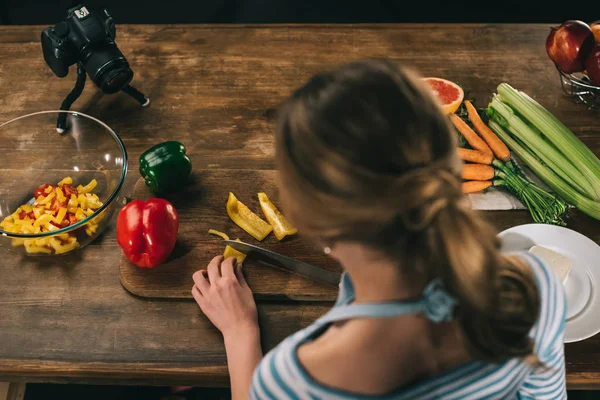 Overhead view of female food blogger cutting bell peppers — Stock Photo