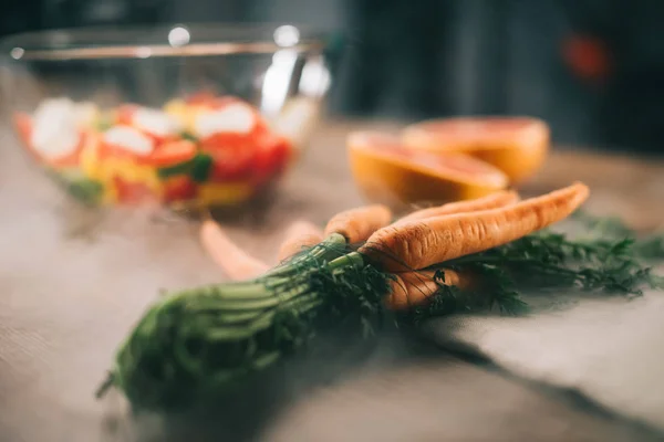 Ripe carrots on wooden table with vegetables on blurred background — Stock Photo
