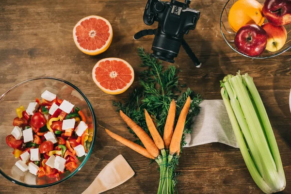 Vista superior da câmera digital e legumes com frutas na mesa de madeira — Fotografia de Stock