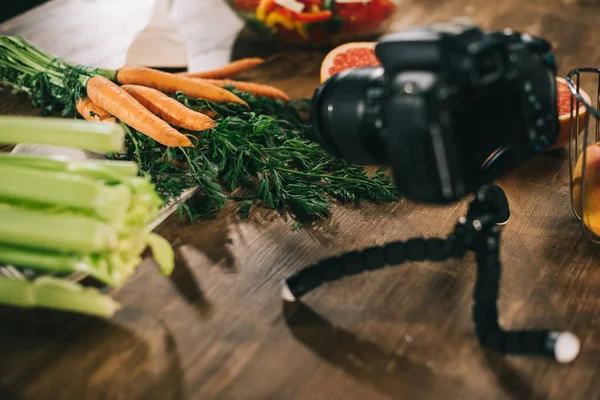 Macchina fotografica digitale e verdure su tavolo di legno — Foto stock
