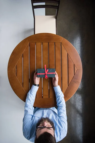 Vue du dessus du bel homme qui attend au café avec présent dans la boîte — Photo de stock